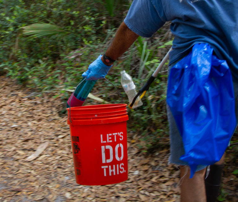 people picking up trash on a tropical trail