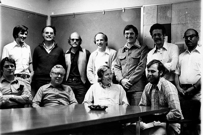 Group portrait of NREL researchers in 1977, arranged in two rows. Front: Jerry Dodd, Jim Gibson, Bill Hunt, and Bill Parton. Back: Jim Detling, Dave Coleman, Jim Ellis, Bob Woodmansee, Mel Dyer, Dave Swift, and Unab Bokhari.